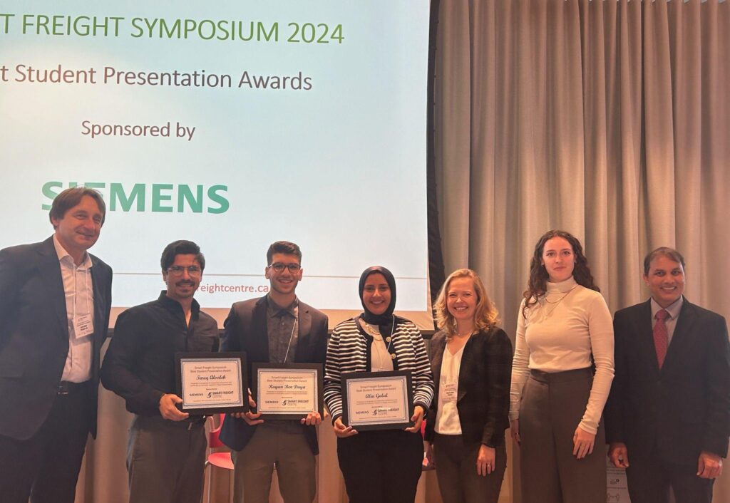 Every winner of a student presentation award stands with their colleagues, proudly showing off their plaques.